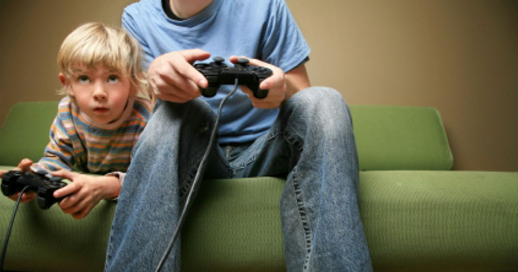 A little kid and his older brother playing video games